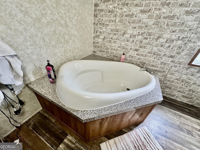 342 Wellington Dr, Byron, GA 31008 - bathroom with brick wall, a garden tub, and wood finished floors