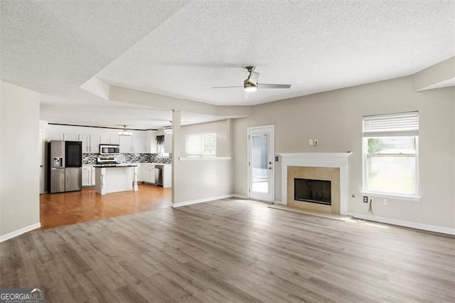 3385 Amhurst Pkwy, South Fulton, GA 30349 - unfurnished living room with a ceiling fan, a textured ceiling, light wood finished floors, healthy amount of natural light, and a fireplace with flush hearth