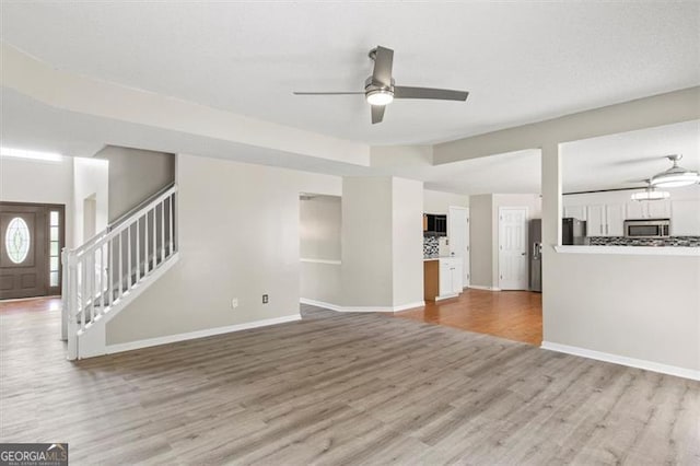 3385 Amhurst Pkwy, South Fulton, GA 30349 - unfurnished living room featuring ceiling fan, wood finished floors, stairway, and baseboards
