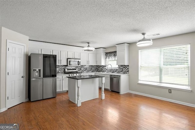 3385 Amhurst Pkwy, South Fulton, GA 30349 - kitchen featuring appliances with stainless steel finishes, backsplash, white cabinetry, wood finished floors, and a textured ceiling