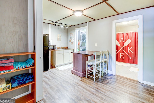 86 Waters Dr, Wedowee, AL 36278 - kitchen featuring stacked washer / drying machine, white cabinets, light wood-style floors, and a kitchen bar