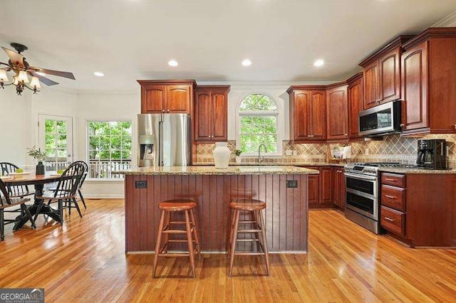 1206 Mountainside Trce NW, Kennesaw, GA 30152 - kitchen featuring appliances with stainless steel finishes, a kitchen bar, ceiling fan, a kitchen island, and light wood-type flooring