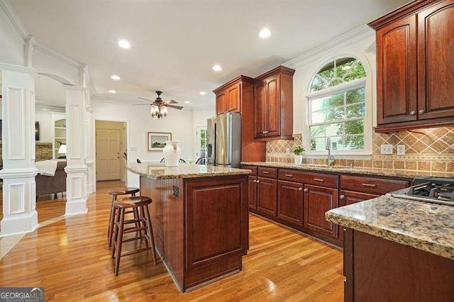 1206 Mountainside Trce NW, Kennesaw, GA 30152 - kitchen featuring stainless steel appliances, a sink, ornate columns, light wood-style floors, and a kitchen breakfast bar