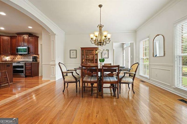 1206 Mountainside Trce NW, Kennesaw, GA 30152 - dining room with light wood finished floors, a decorative wall, a chandelier, ornamental molding, and arched walkways
