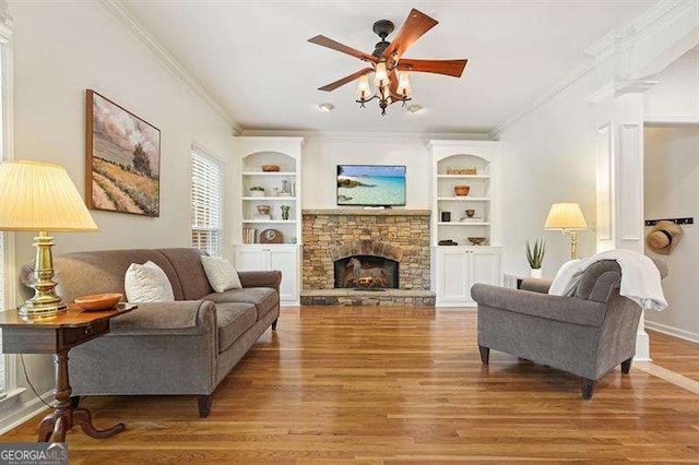 1206 Mountainside Trce NW, Kennesaw, GA 30152 - living area featuring wood finished floors, ornamental molding, a stone fireplace, ceiling fan, and built in shelves