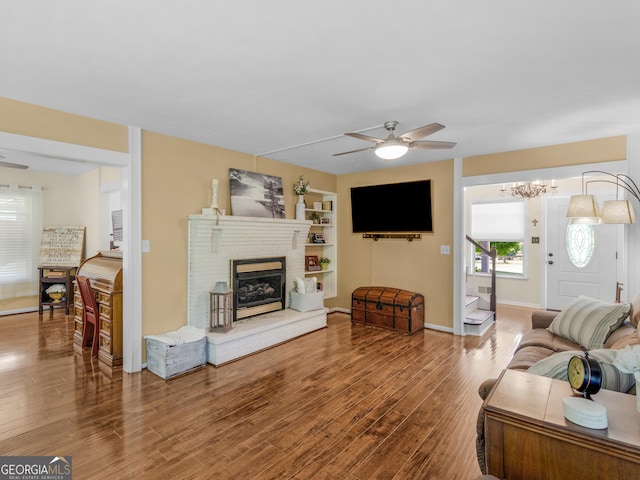 571 Swint Rd, Griffin, GA 30224 - living room featuring wood finished floors, a ceiling fan, a brick fireplace, baseboards, and a chandelier