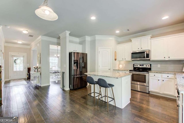 1300 Jefferson Walk Cir, Jefferson, GA 30549 - kitchen with stainless steel appliances, light stone countertops, decorative backsplash, a kitchen island, and ornamental molding