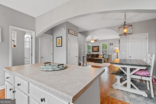 106 Thornton Dr, Bonaire, GA 31005 - kitchen featuring arched walkways, light wood-type flooring, white cabinets, and pendant lighting
