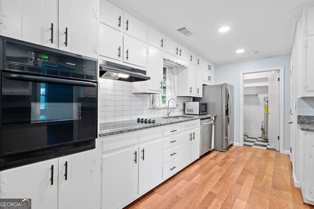 3047 Hudson Ct, Decatur, GA 30033 - kitchen with black appliances, decorative backsplash, under cabinet range hood, white cabinets, and light wood-style flooring