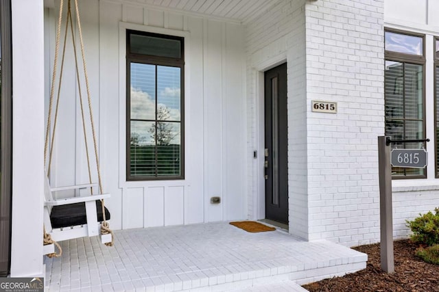 6815 Halcyon Way, Alpharetta, GA 30005 - doorway to property with brick siding, covered porch, and board and batten siding