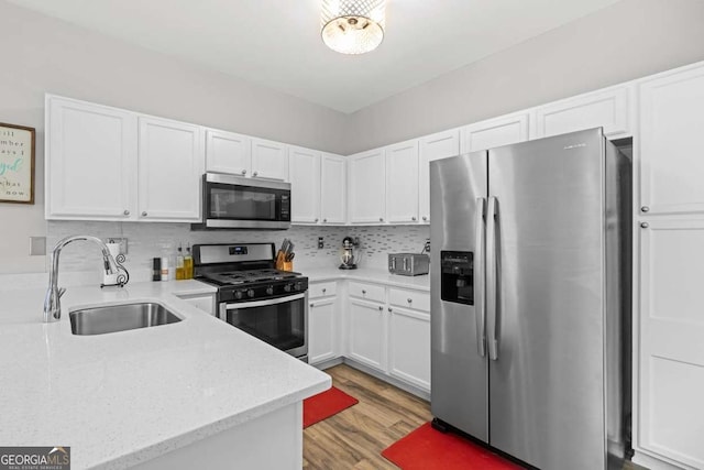 2061 Pinnacle Pointe Dr, Norcross, GA 30071 - kitchen with appliances with stainless steel finishes, a sink, white cabinetry, light wood-style floors, and light stone countertops