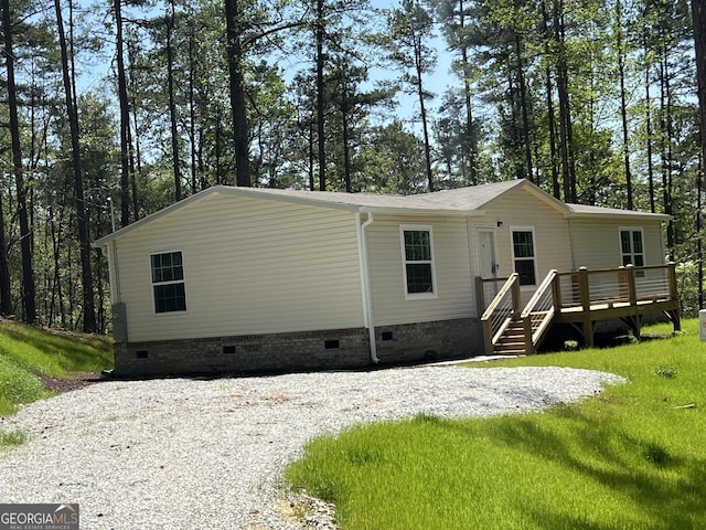 69 Cheyenne Trl, Martin, GA 30557 - view of front facade featuring crawl space, a deck, gravel driveway, a front yard, and view of scattered trees