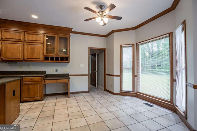 214 Jamestown Ave, Jonesboro, GA 30236 - kitchen with brown cabinetry, ceiling fan, dark countertops, ornamental molding, and glass insert cabinets