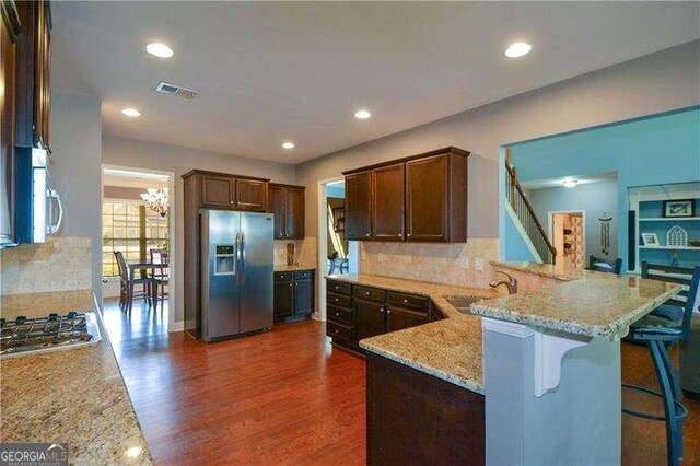 1480 Waverly Glen Dr, Alpharetta, GA 30004 - kitchen featuring appliances with stainless steel finishes, dark wood-style flooring, a peninsula, light stone counters, and tasteful backsplash