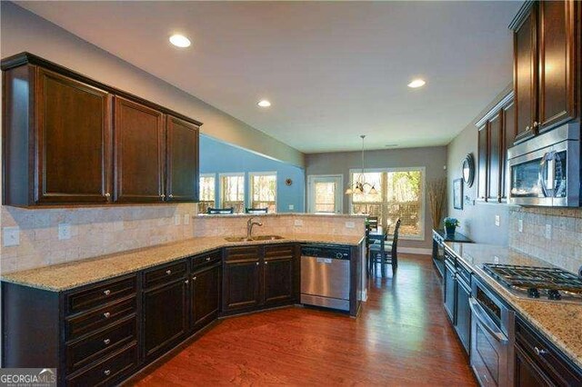 1480 Waverly Glen Dr, Alpharetta, GA 30004 - kitchen featuring stainless steel appliances, a peninsula, dark wood finished floors, light stone counters, and dark brown cabinetry