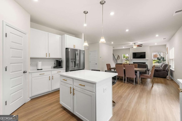 228 Whitneys Way, Dallas, GA 30157 - kitchen featuring stainless steel fridge with ice dispenser, a ceiling fan, a fireplace, light wood-type flooring, and light countertops