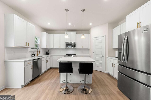 228 Whitneys Way, Dallas, GA 30157 - kitchen with appliances with stainless steel finishes, a kitchen island, light countertops, light wood-type flooring, and recessed lighting