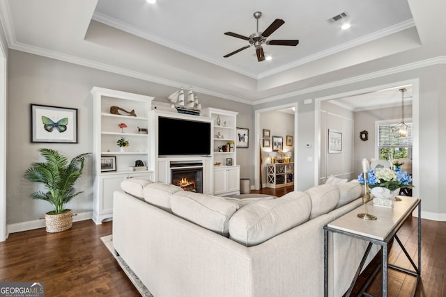 109 Carrington Ct, Kingsland, GA 31548 - living room featuring dark wood finished floors, ceiling fan, a warm lit fireplace, a tray ceiling, and crown molding
