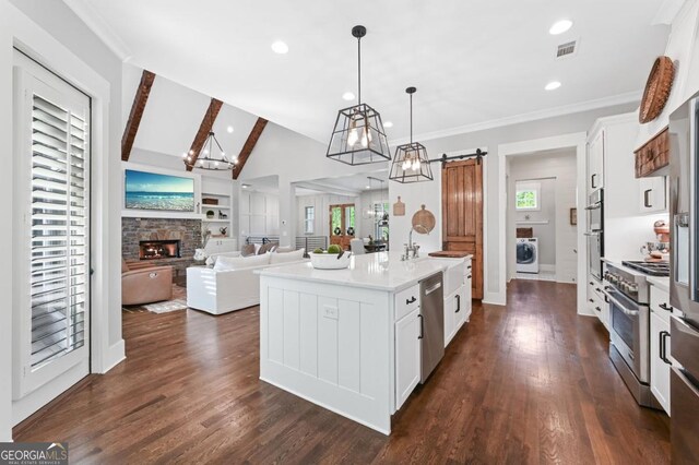221 Goss Ln, Ball Ground, GA 30107 - kitchen featuring appliances with stainless steel finishes, washer / dryer, a fireplace, vaulted ceiling, and white cabinets