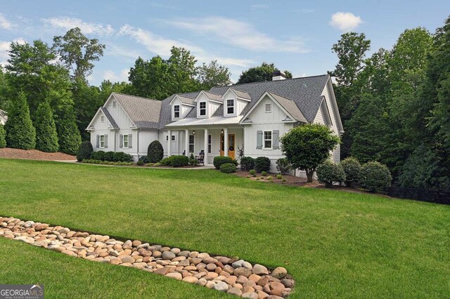 221 Goss Ln, Ball Ground, GA 30107 - new england style home featuring board and batten siding, covered porch, a front yard, and a chimney
