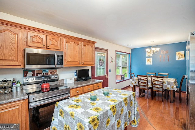 259 Hanover Cir SE, Calhoun, GA 30701 - kitchen featuring stainless steel appliances, a chandelier, wood finished floors, brown cabinetry, and pendant lighting