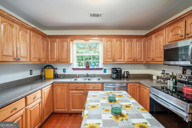 259 Hanover Cir SE, Calhoun, GA 30701 - kitchen featuring stainless steel appliances, wood finished floors, brown cabinetry, and dark countertops