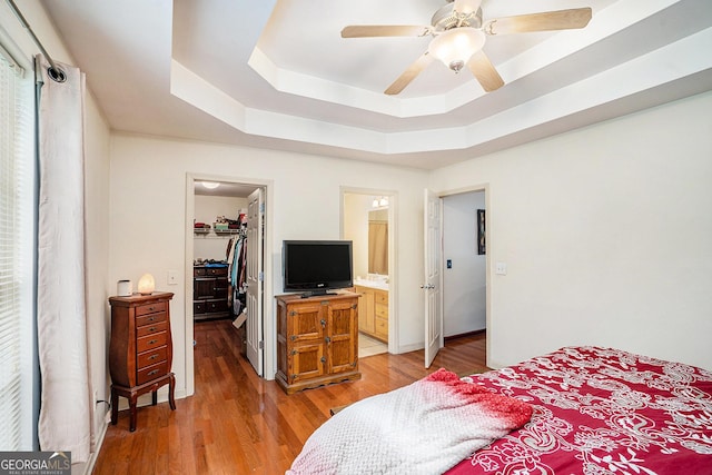 259 Hanover Cir SE, Calhoun, GA 30701 - bedroom featuring a walk in closet, a raised ceiling, light wood-style flooring, a closet, and a ceiling fan