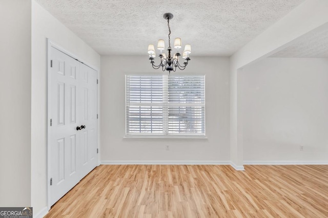 1186 Hawthorn Ln, Grayson, GA 30017 - unfurnished dining area with a chandelier, light wood-type flooring, and a textured ceiling