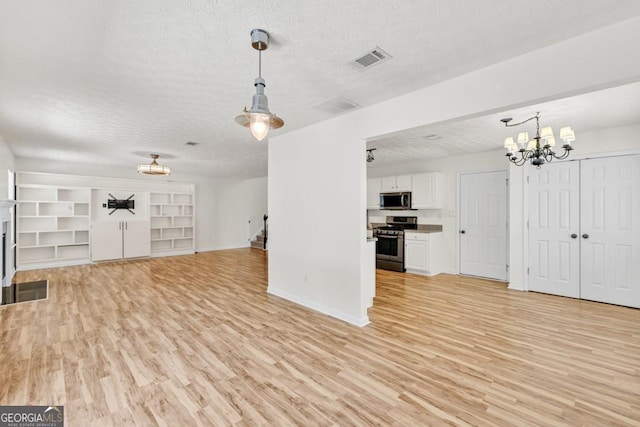 1186 Hawthorn Ln, Grayson, GA 30017 - unfurnished living room featuring a textured ceiling, light wood finished floors, and a chandelier