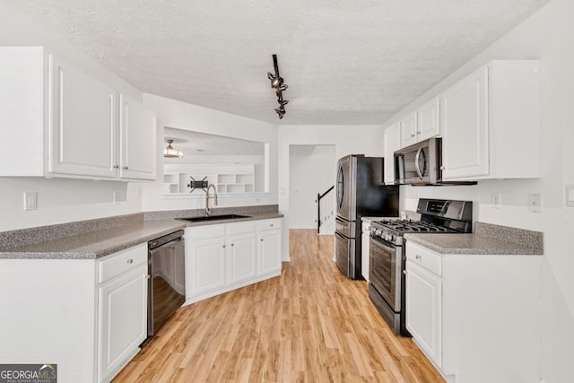 1186 Hawthorn Ln, Grayson, GA 30017 - kitchen with stainless steel appliances, light wood finished floors, white cabinetry, a textured ceiling, and rail lighting