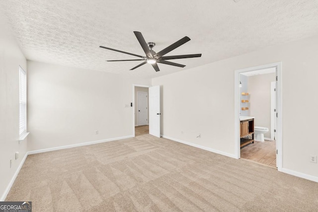 1186 Hawthorn Ln, Grayson, GA 30017 - unfurnished bedroom with light colored carpet, a textured ceiling, connected bathroom, and a ceiling fan