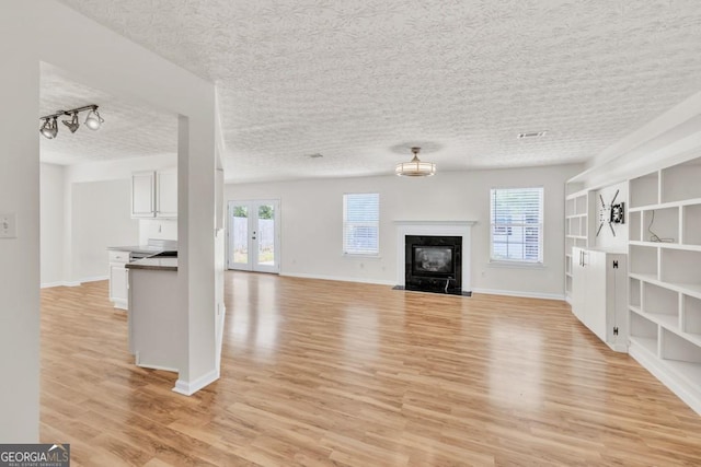 1186 Hawthorn Ln, Grayson, GA 30017 - unfurnished living room featuring light wood-style floors, a textured ceiling, and a high end fireplace