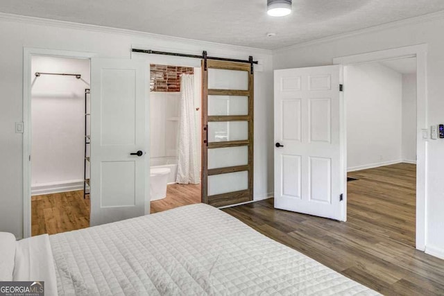2572 Bates St SE, Smyrna, GA 30080 - bedroom featuring a barn door, wood finished floors, crown molding, baseboards, and ensuite bath