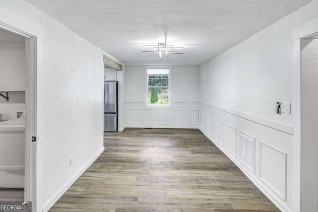 2572 Bates St SE, Smyrna, GA 30080 - unfurnished dining area featuring wood finished floors, a textured ceiling, and wainscoting