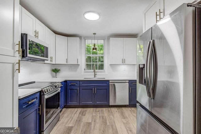 2572 Bates St SE, Smyrna, GA 30080 - kitchen featuring stainless steel appliances, blue cabinetry, a sink, white cabinets, and light wood-style floors