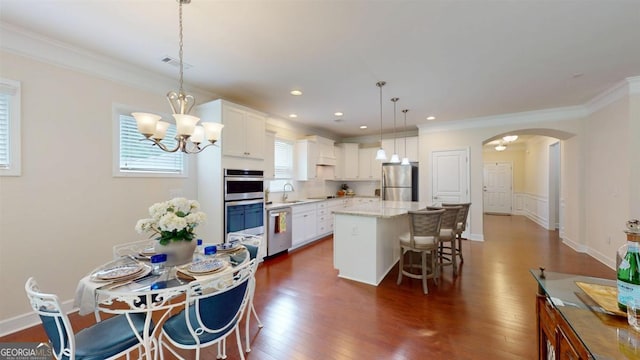 1391 Crooked Creek Rd, Greensboro, GA 30642 - kitchen featuring appliances with stainless steel finishes, a sink, a kitchen breakfast bar, arched walkways, and dark wood-style floors
