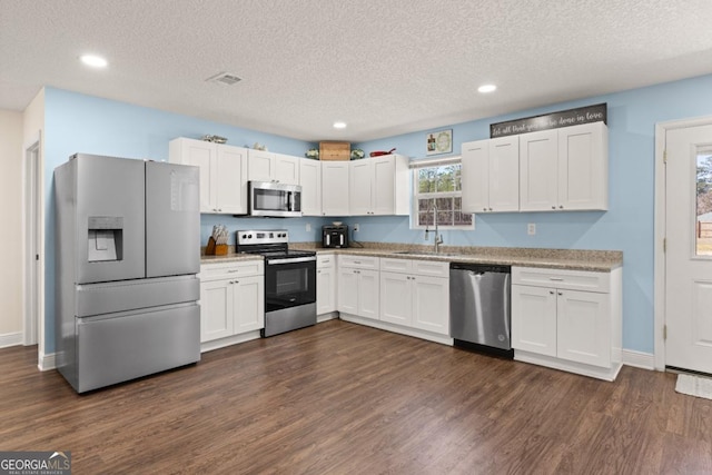 825 Red Hawk Dr, Waynesville, GA 31566 - kitchen with stainless steel appliances, white cabinetry, dark wood-style floors, a textured ceiling, and light countertops