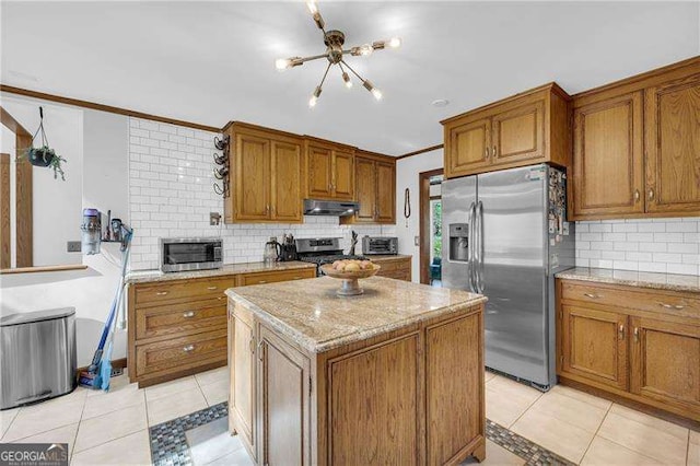10845 Shallowford Rd, Roswell, GA 30075 - kitchen with stainless steel appliances, a chandelier, under cabinet range hood, tasteful backsplash, and brown cabinetry