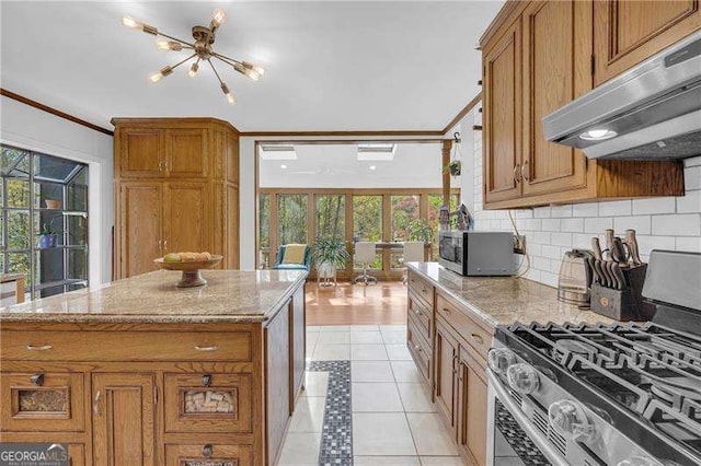 10845 Shallowford Rd, Roswell, GA 30075 - kitchen with stainless steel gas range oven, under cabinet range hood, brown cabinets, decorative backsplash, and light stone counters