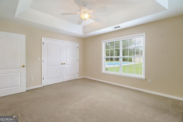 101 Coldbrook Cir, Rincon, GA 31326 - unfurnished bedroom featuring a tray ceiling, carpet flooring, a closet, and a ceiling fan