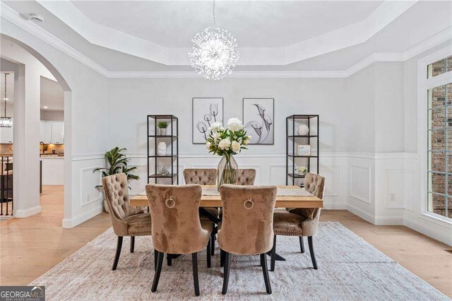 5705 Registry Oaks Ln SE, Mableton, GA 30126 - dining area with a tray ceiling, a chandelier, light wood-style flooring, arched walkways, and ornamental molding