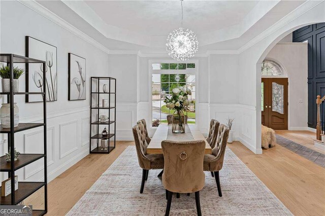 5705 Registry Oaks Ln SE, Mableton, GA 30126 - dining room with a tray ceiling, a chandelier, arched walkways, a decorative wall, and light wood-type flooring