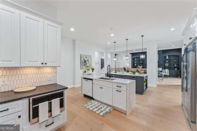 5705 Registry Oaks Ln SE, Mableton, GA 30126 - kitchen with a sink, appliances with stainless steel finishes, an island with sink, backsplash, and light wood-style floors