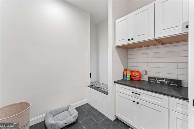 5705 Registry Oaks Ln SE, Mableton, GA 30126 - kitchen featuring dark countertops, white cabinetry, tasteful backsplash, dark tile patterned floors, and baseboards