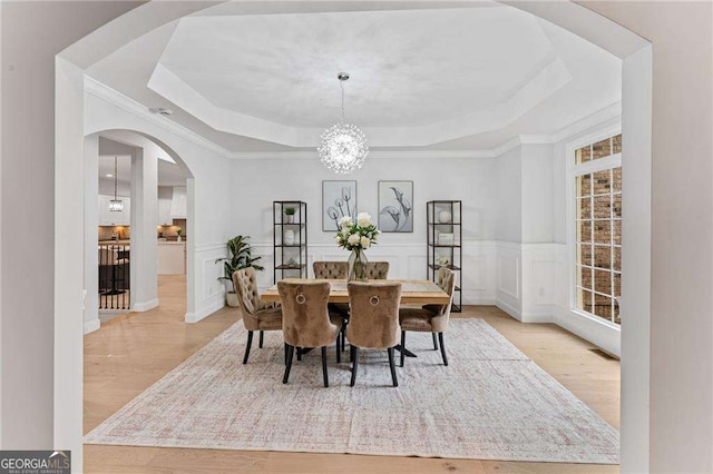 5705 Registry Oaks Ln SE, Mableton, GA 30126 - dining space featuring a raised ceiling, arched walkways, light wood finished floors, a chandelier, and crown molding