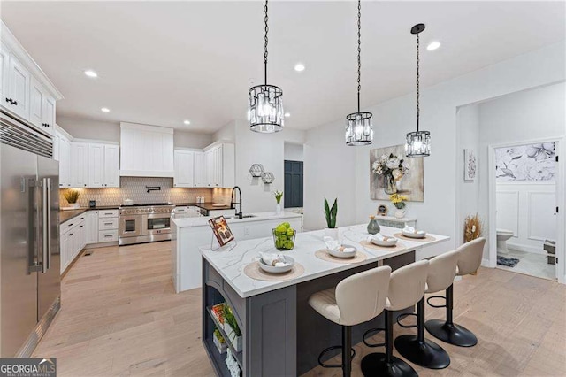 5705 Registry Oaks Ln SE, Mableton, GA 30126 - kitchen with high quality appliances, premium range hood, tasteful backsplash, white cabinets, and light wood-style flooring