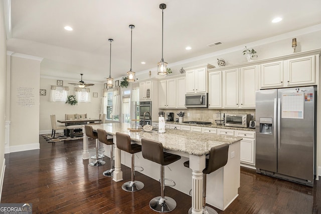 6861 Louis Dr, Locust Grove, GA 30248 - kitchen featuring appliances with stainless steel finishes, tasteful backsplash, a kitchen island with sink, dark wood finished floors, and a kitchen breakfast bar
