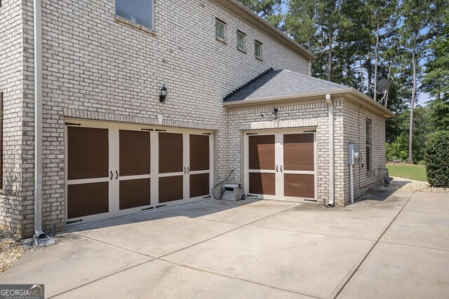6861 Louis Dr, Locust Grove, GA 30248 - back of house featuring driveway, a shingled roof, brick siding, and french doors