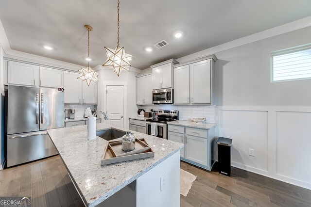 4581 Blacksmith Ln, Jefferson, GA 30549 - kitchen with appliances with stainless steel finishes, a sink, a kitchen island with sink, light stone countertops, and wainscoting