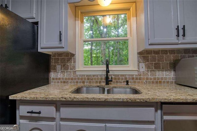 34 Sassafras Grv, Dawsonville, GA 30534 - kitchen featuring a sink, freestanding refrigerator, backsplash, light stone counters, and white cabinetry